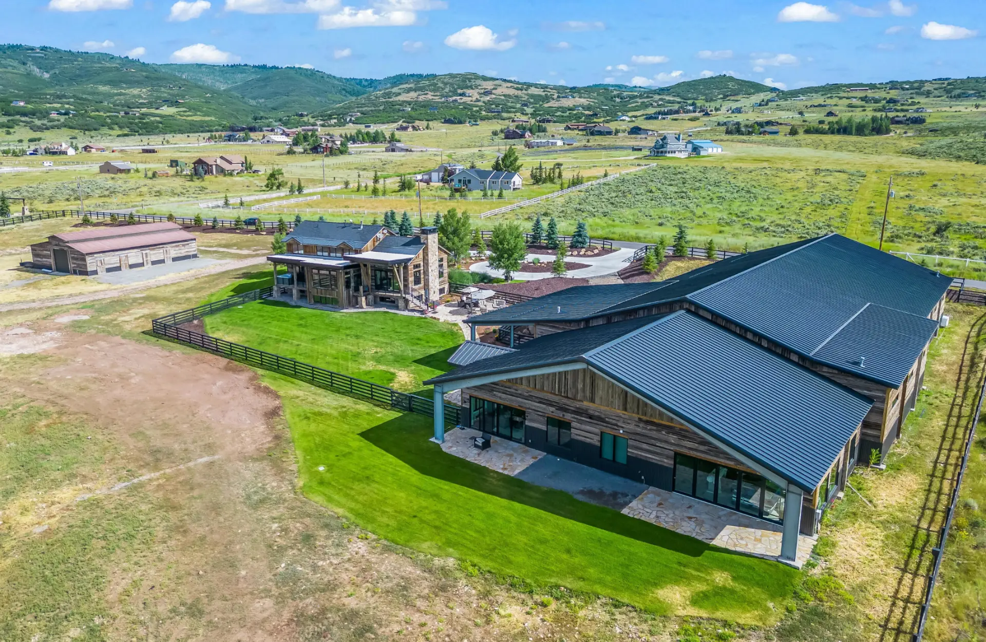 An aerial view of the private Park City estate, its lodge and lawn set among rolling green hills
