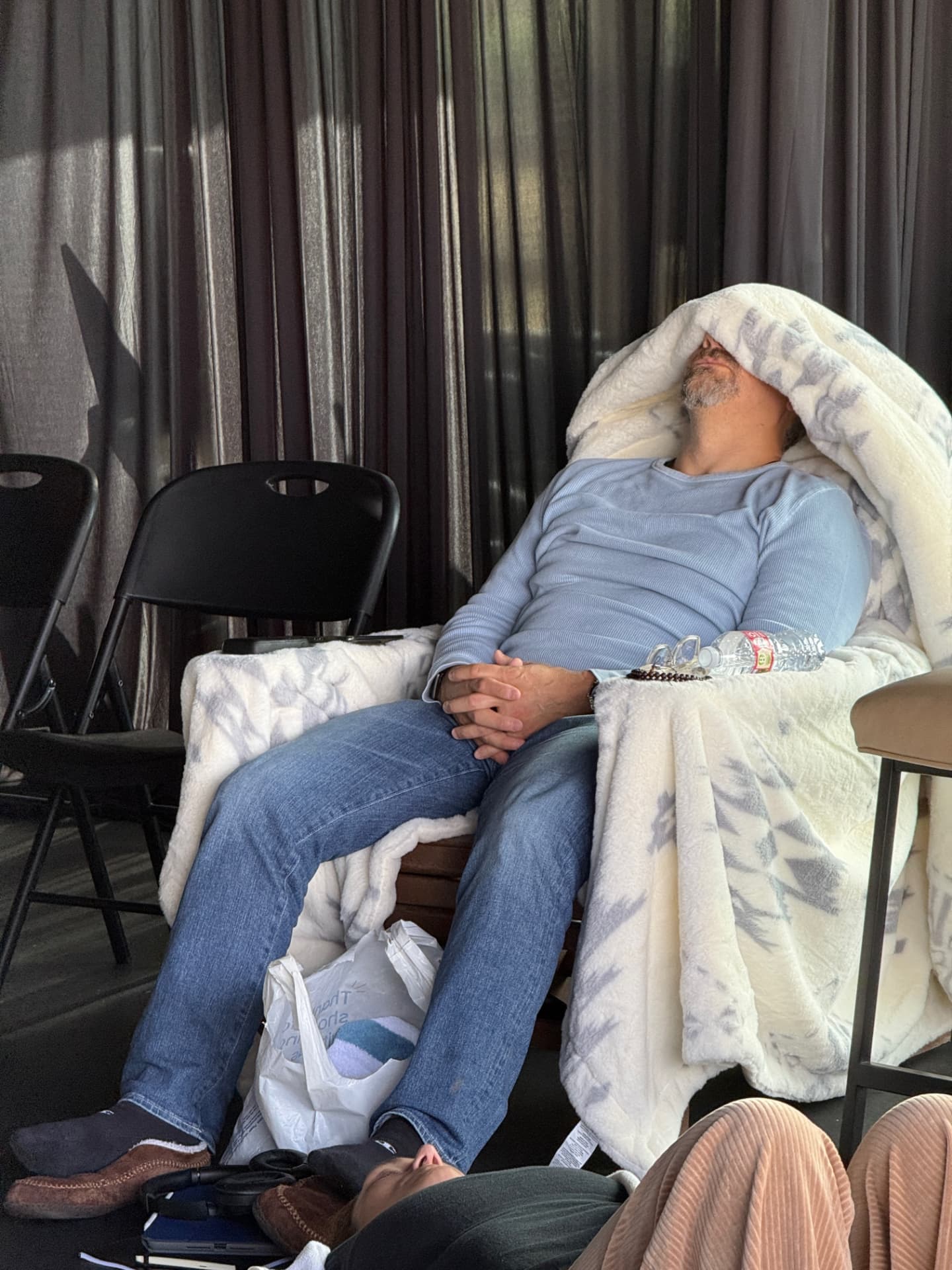 A participant resting under a blanket in a quiet corner of the session room