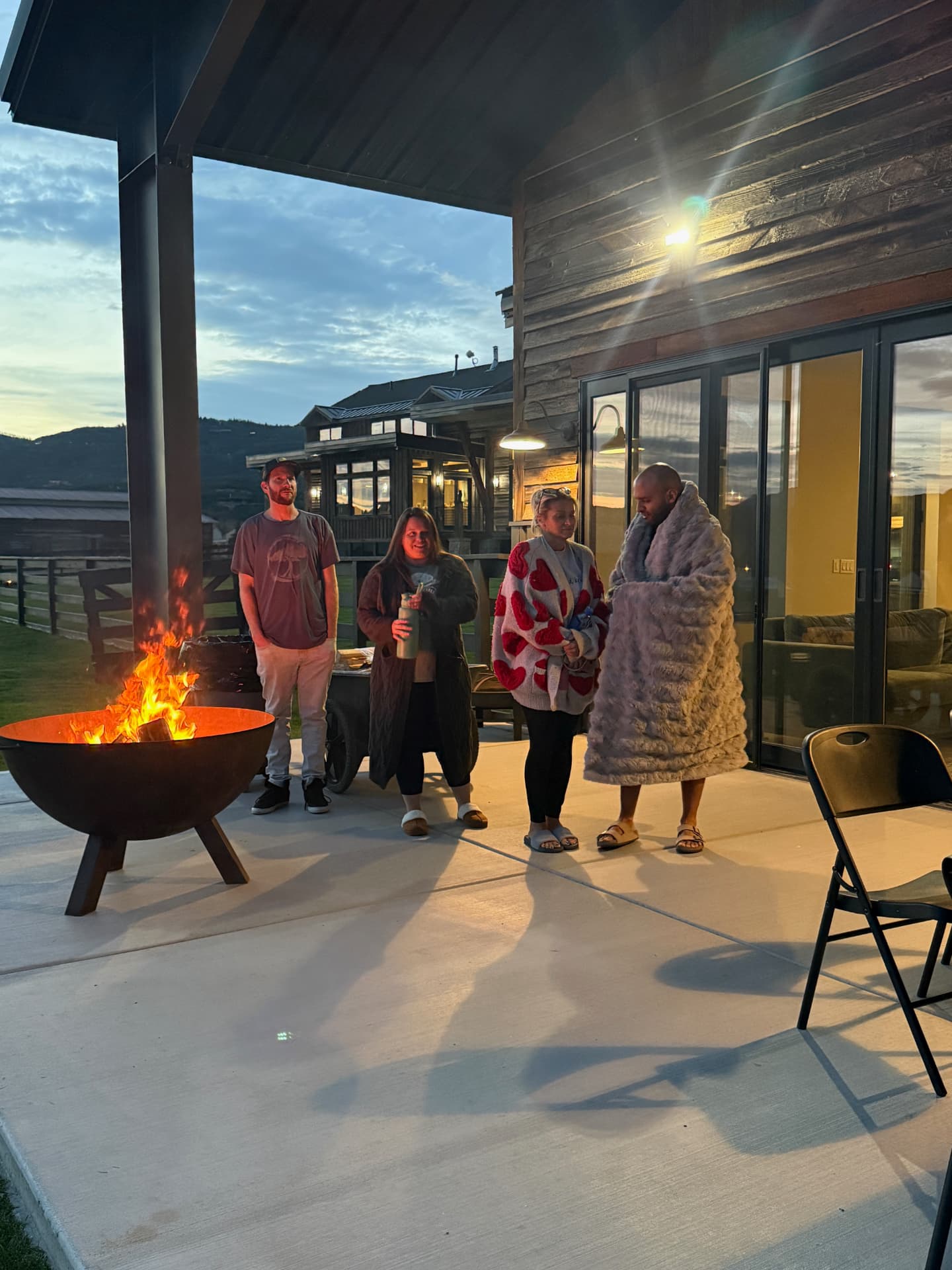 Participants standing around an outdoor fire pit at sunset outside the estate