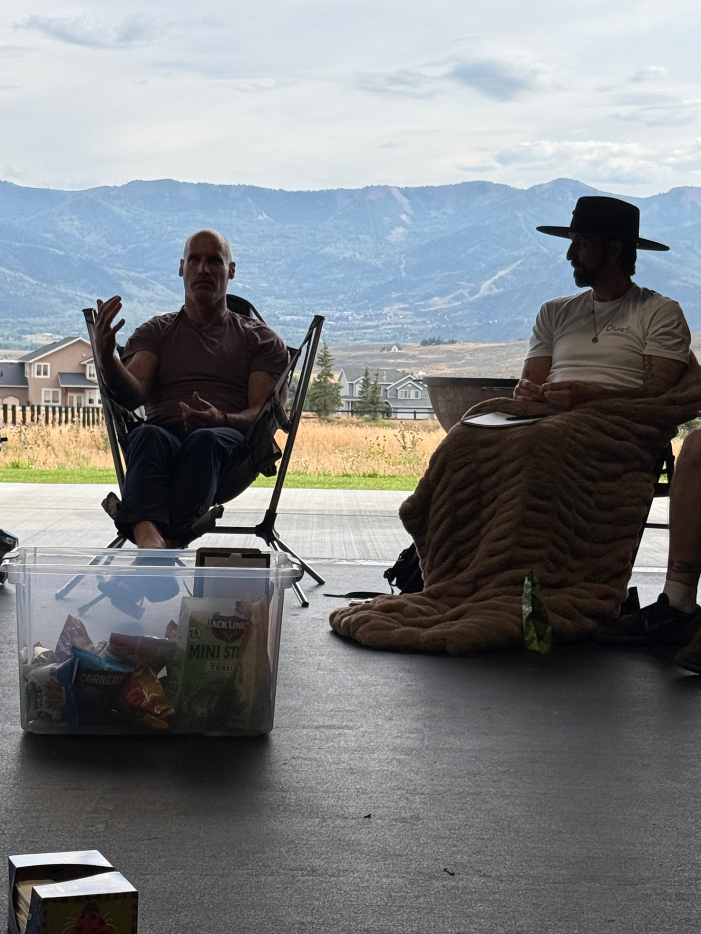 Two facilitators in conversation on an open-air patio with the Park City mountains behind them